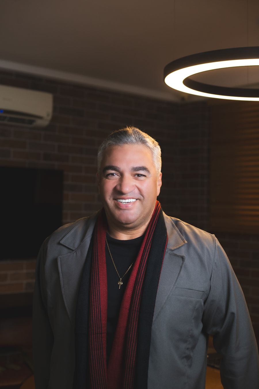 Alex Gomes, da Postura Espiritual, sorrindo em retrato com cachecol vermelho